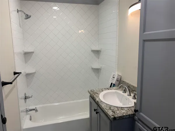a bathroom with a granite countertop sink and a bathtub