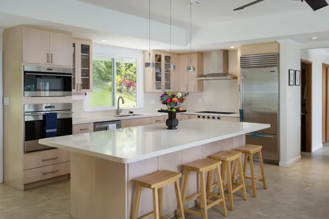 a kitchen with stainless steel appliances kitchen island granite countertop a table chairs microwave and sink