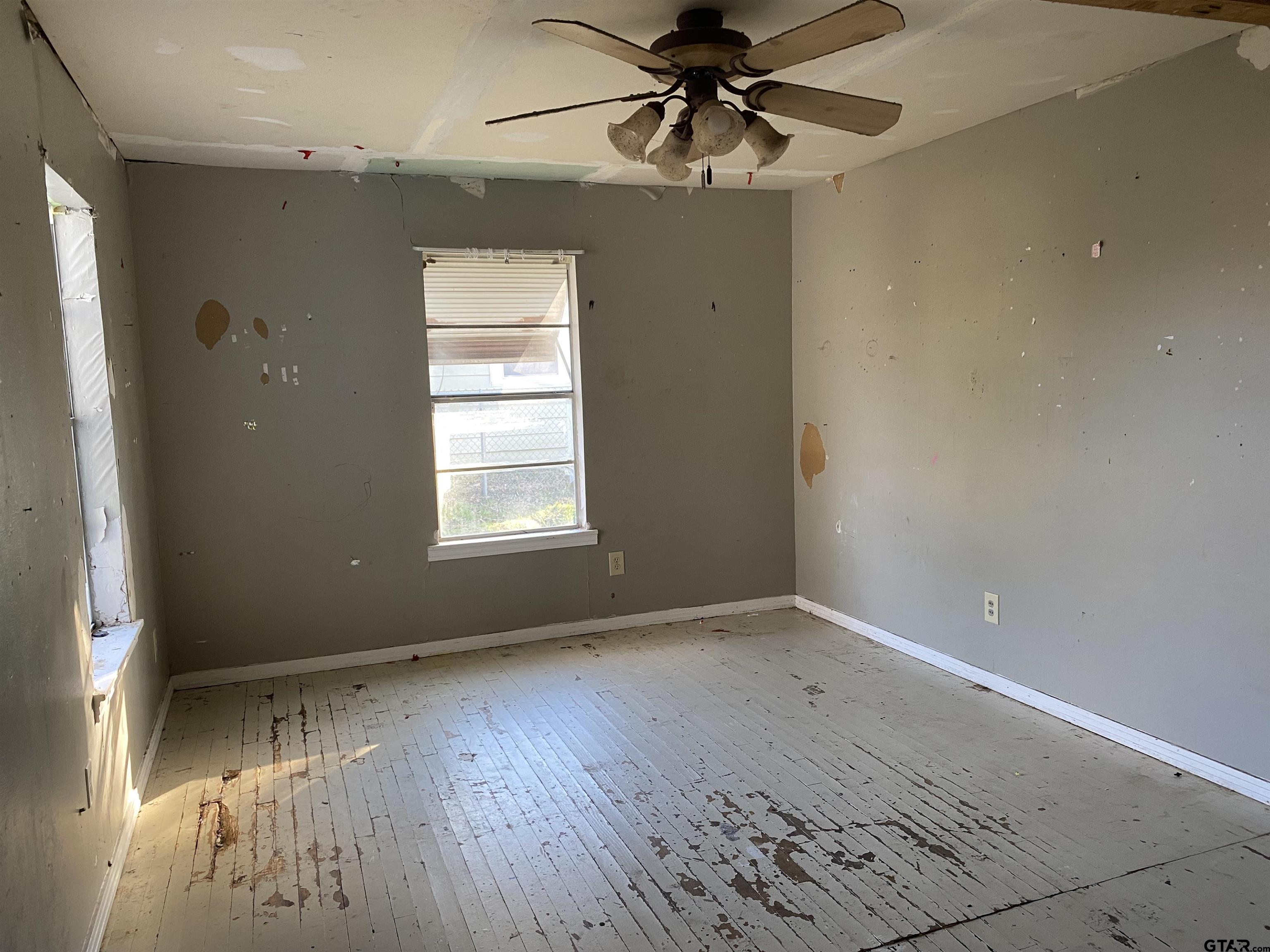 210 North Stephens Street Quitman, TX 75783 - Photo 12 of 28 an empty room with wooden floor chandelier fan and windows