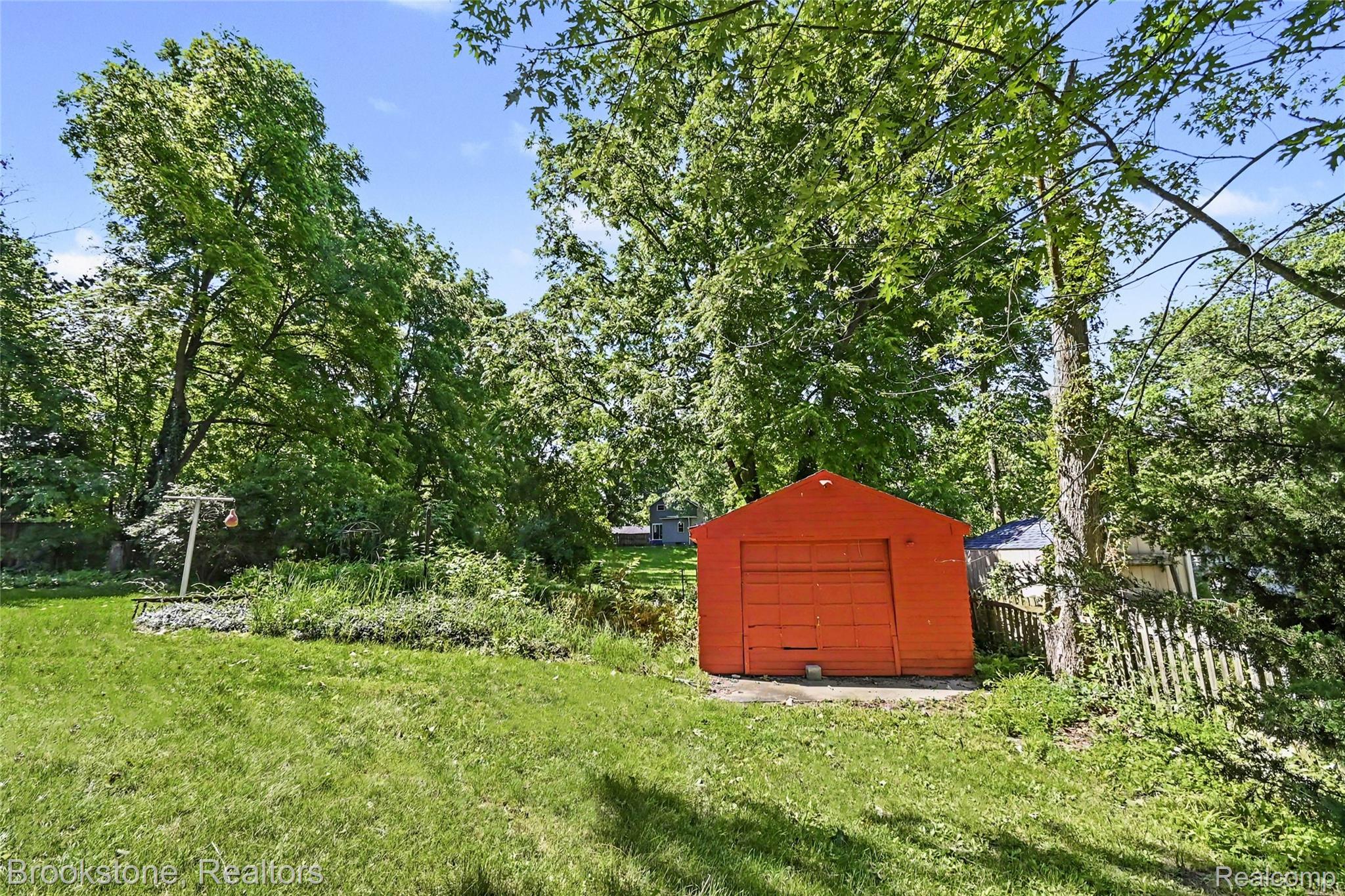 416 East Maple Street Mason, MI 48854 - Photo 17 of 18 Expansive green lawn featuring a detached red storage shed with a roll-up door