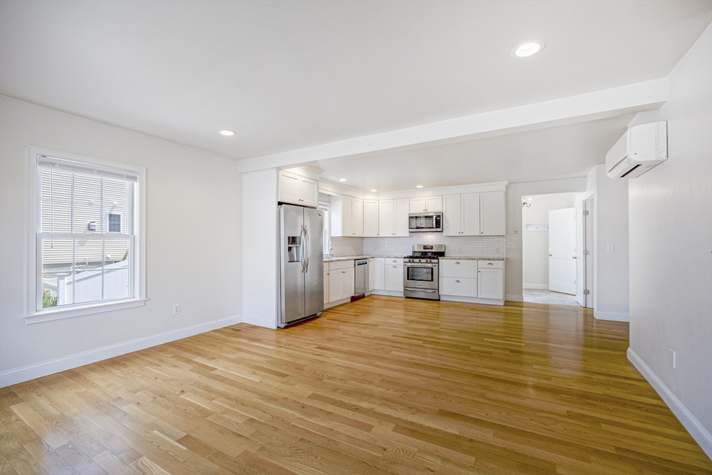 48 Spruce Street, Unit 1 Winchester, MA 01890 - Photo 1 of 29 a large white kitchen with kitchen island granite countertop a refrigerator and window