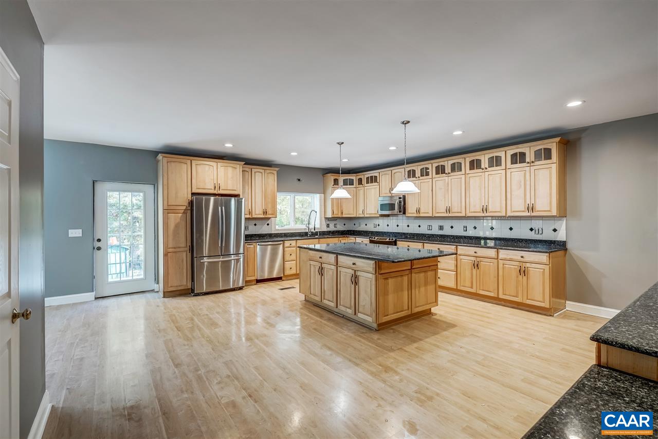 a large kitchen with stainless steel appliances granite countertop a refrigerator and a stove top oven