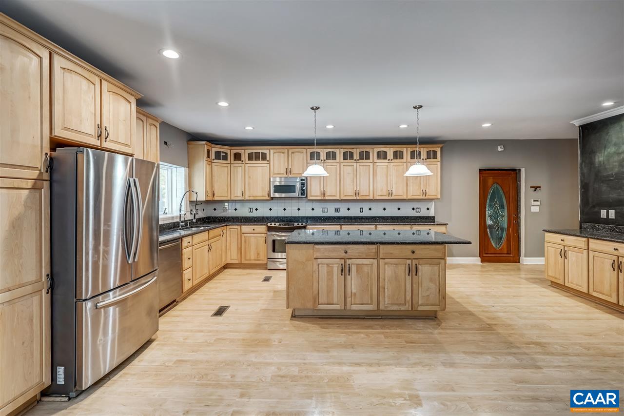 5595 New Line Road Gum Spring, VA 23065 - Photo 12 of 36 a large kitchen with granite countertop a large refrigerator a sink and white cabinets