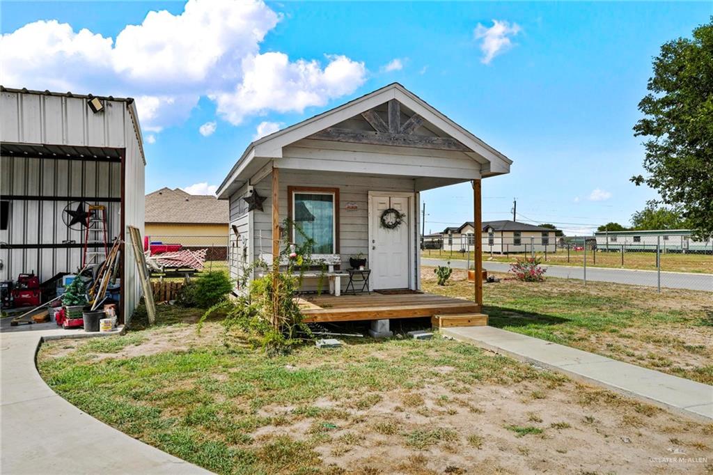 23247 Uresti Road Edinburg, TX 78542 - Photo 14 of 18 Siding exterior with a covered porch, wood-framed window, and a concrete walkway