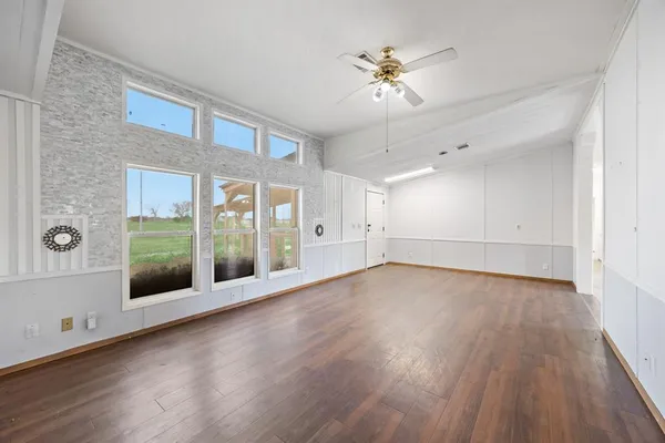 a view of an empty room with glass door and wooden floor