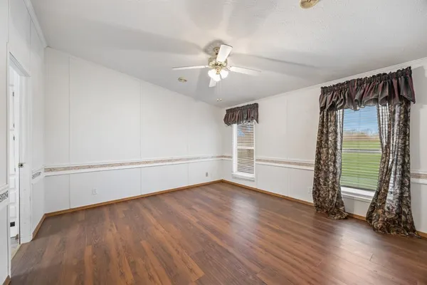 an empty room with wooden floor fan and windows