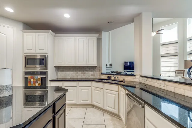 a kitchen with stainless steel appliances granite countertop a sink and cabinets with wooden floor