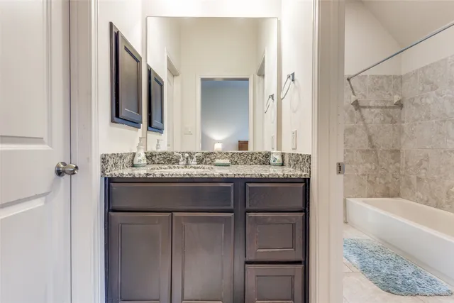 a bathroom with a granite countertop sink and a mirror a bathtub