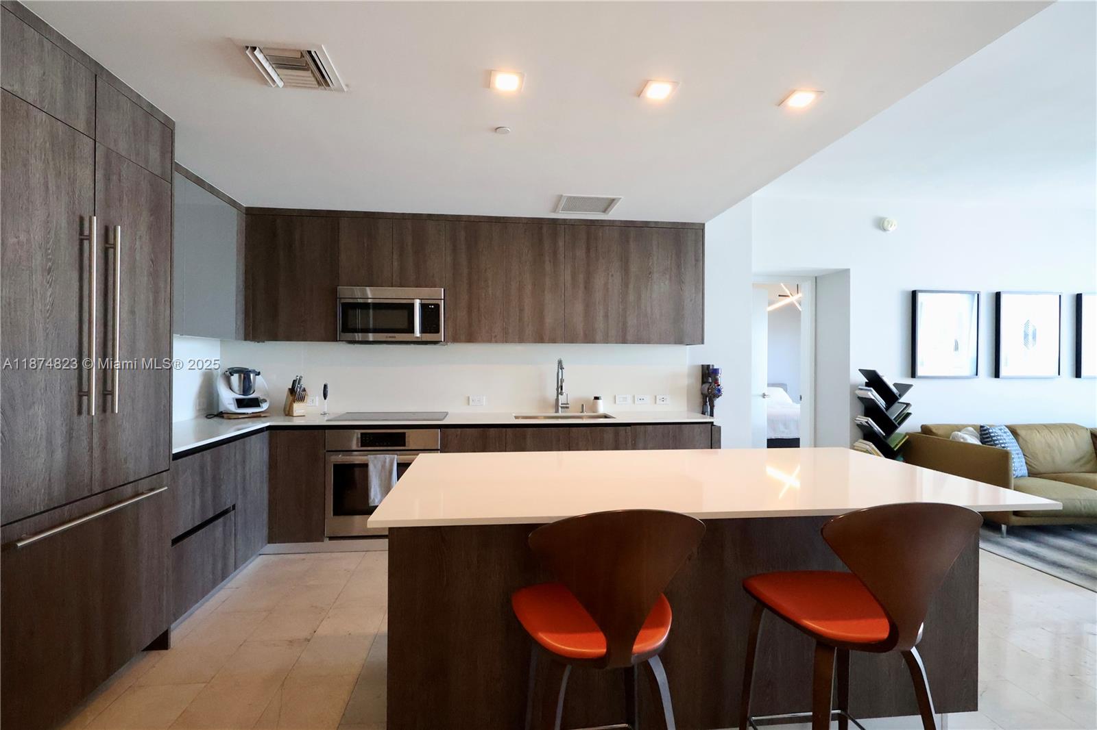 68 Southeast 6th Street, Unit 3607 Miami, FL 33131 - Photo 2 of 29 a large kitchen with kitchen island a dining table and chairs