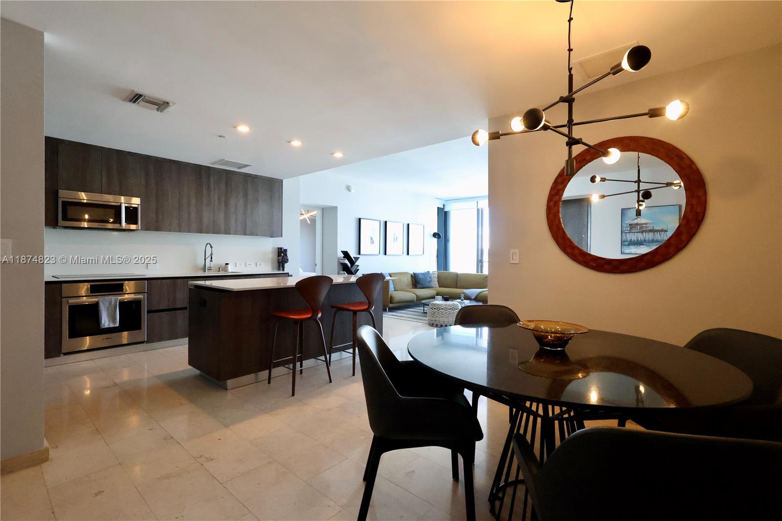68 Southeast 6th Street, Unit 3607 Miami, FL 33131 - Photo 4 of 29 a kitchen with a dining table chairs and a refrigerator