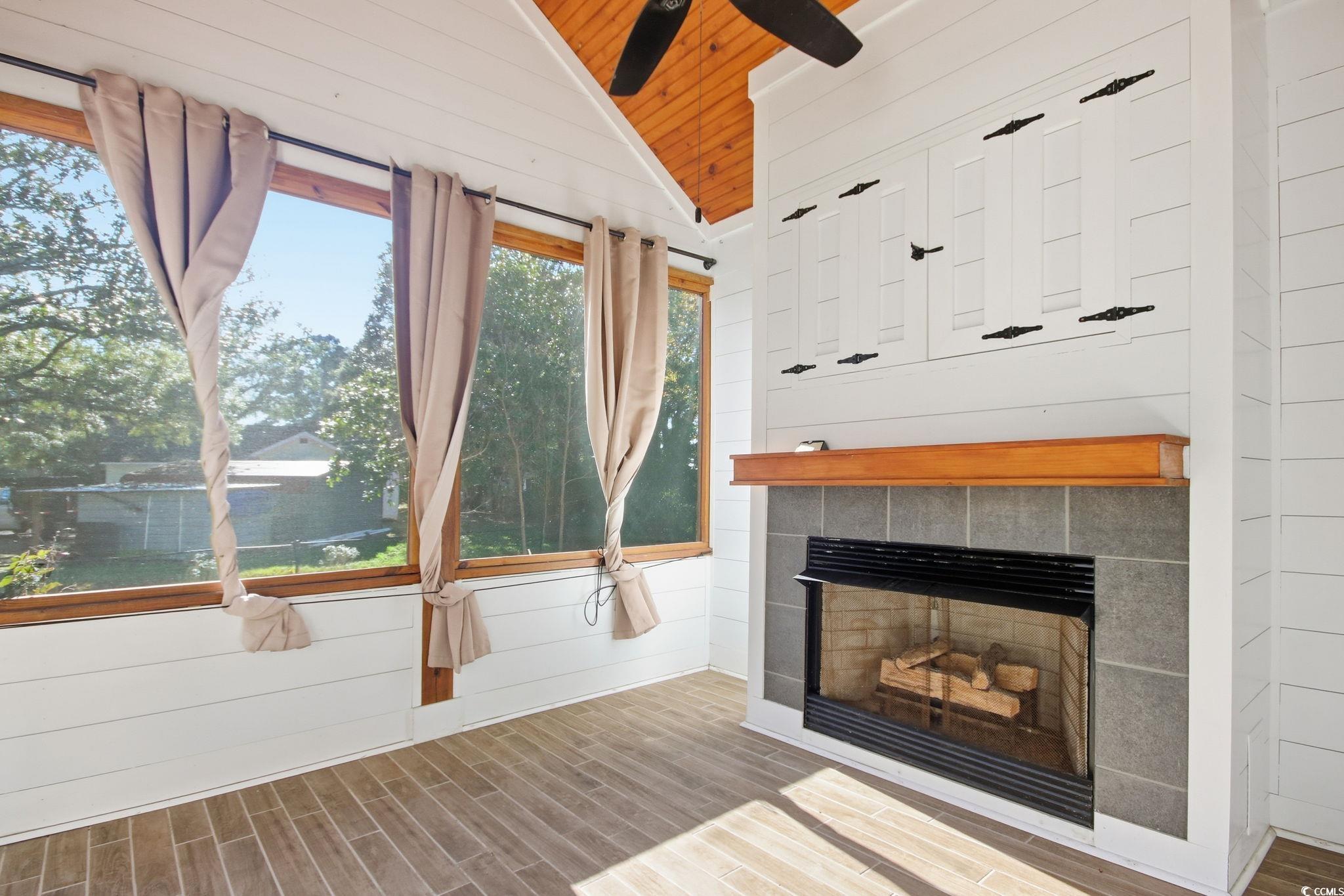 1735 Rice Street Georgetown, SC 29440 - Photo 14 of 34 Unfurnished living room featuring wood tiled floors, lofted ceiling, a tiled fireplace, wood walls, and wood ceiling