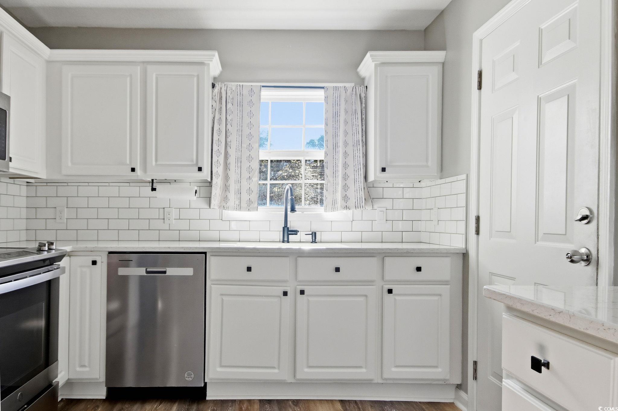1735 Rice Street Georgetown, SC 29440 - Photo 5 of 34 Kitchen with light stone counters, white cabinets, appliances with stainless steel finishes, decorative backsplash, and dark wood finished floors