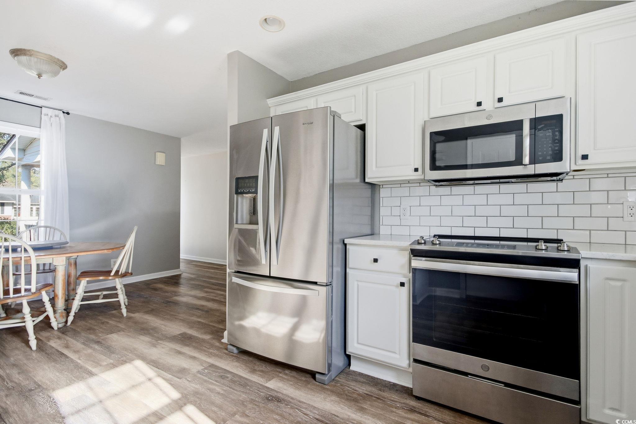 1735 Rice Street Georgetown, SC 29440 - Photo 6 of 34 Kitchen featuring stainless steel appliances, white cabinets, backsplash, light wood finished floors, and light stone countertops