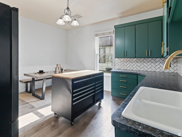 158 East 300 South Logan, UT 84321 - Photo 12 of 25 Kitchen featuring freestanding refrigerator, dark wood-style flooring, green cabinets, backsplash, and a chandelier
