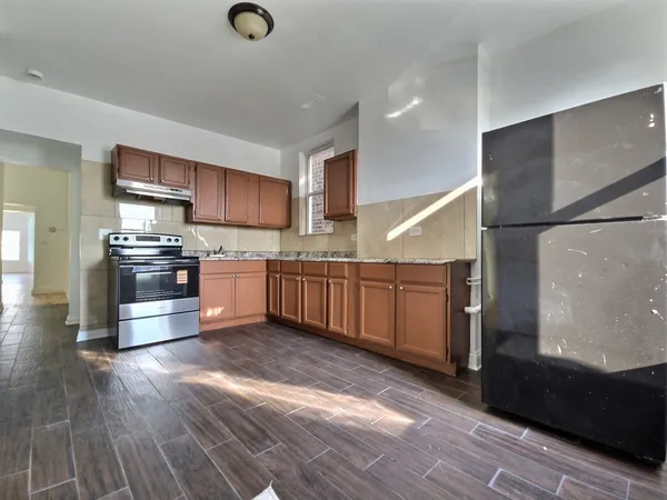 a kitchen with stainless steel appliances granite countertop a refrigerator a stove and a sink with wooden floor