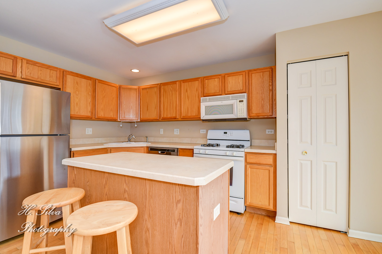 9425 Rainsford Drive Huntley, IL 60142 - Photo 4 of 15 a kitchen with stainless steel appliances granite countertop a sink a stove a refrigerator a microwave oven with white cabinets and wooden floor