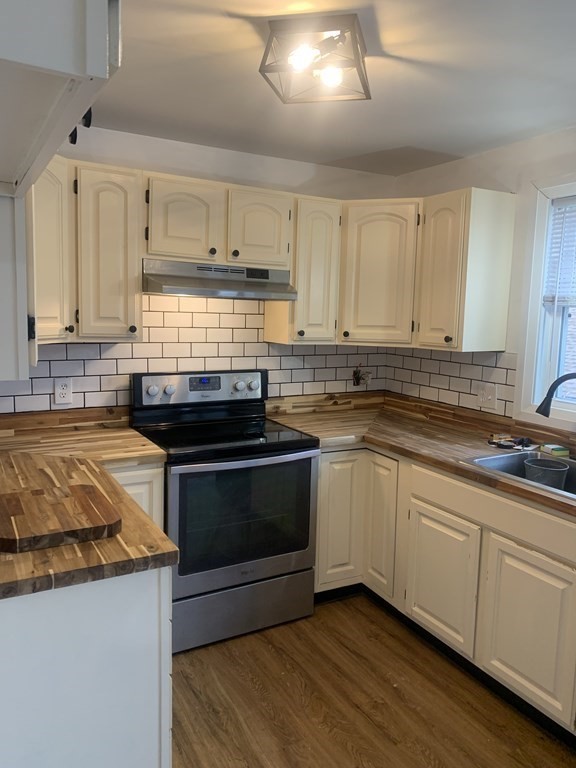 111 Warrenton Street Springfield, MA 01109 - Photo 4 of 18 a kitchen with granite countertop a sink dishwasher a stove and white cabinets