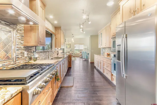 a large kitchen with stainless steel appliances kitchen island granite countertop a large counter top a stove a sink dishwasher a refrigerator and cabinets with wooden floor