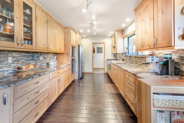 a large kitchen with stainless steel appliances granite countertop a lot of counter space and wooden floors