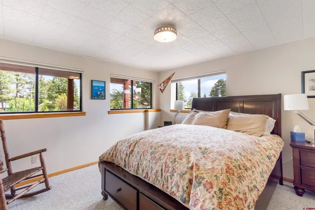 a bedroom with a large bed and a lamp on dresser