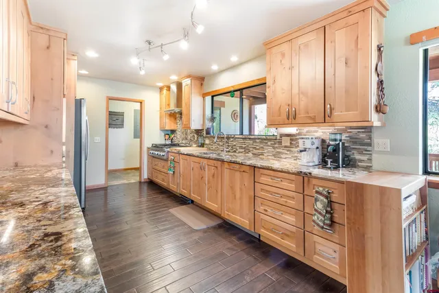 a kitchen with stainless steel appliances kitchen island granite countertop a stove a sink and white cabinets with wooden floor