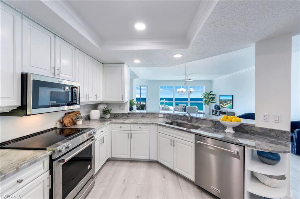 269 Barefoot Beach Boulevard, Unit 403 Bonita Springs, FL 34134 - Photo 8 of 27 Kitchen featuring stainless steel appliances, a sink, a tray ceiling, crown molding, and a chandelier