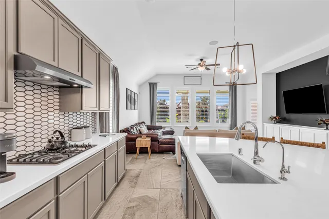 a large kitchen with a sink and living room view