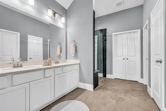 a spacious bathroom with a double vanity sink a mirror and a shower