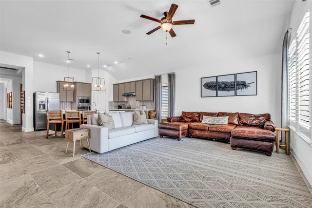 a living room with furniture kitchen view and a window