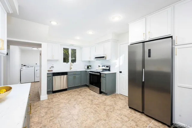 a large kitchen with a refrigerator a sink a counter top space and stainless steel appliances