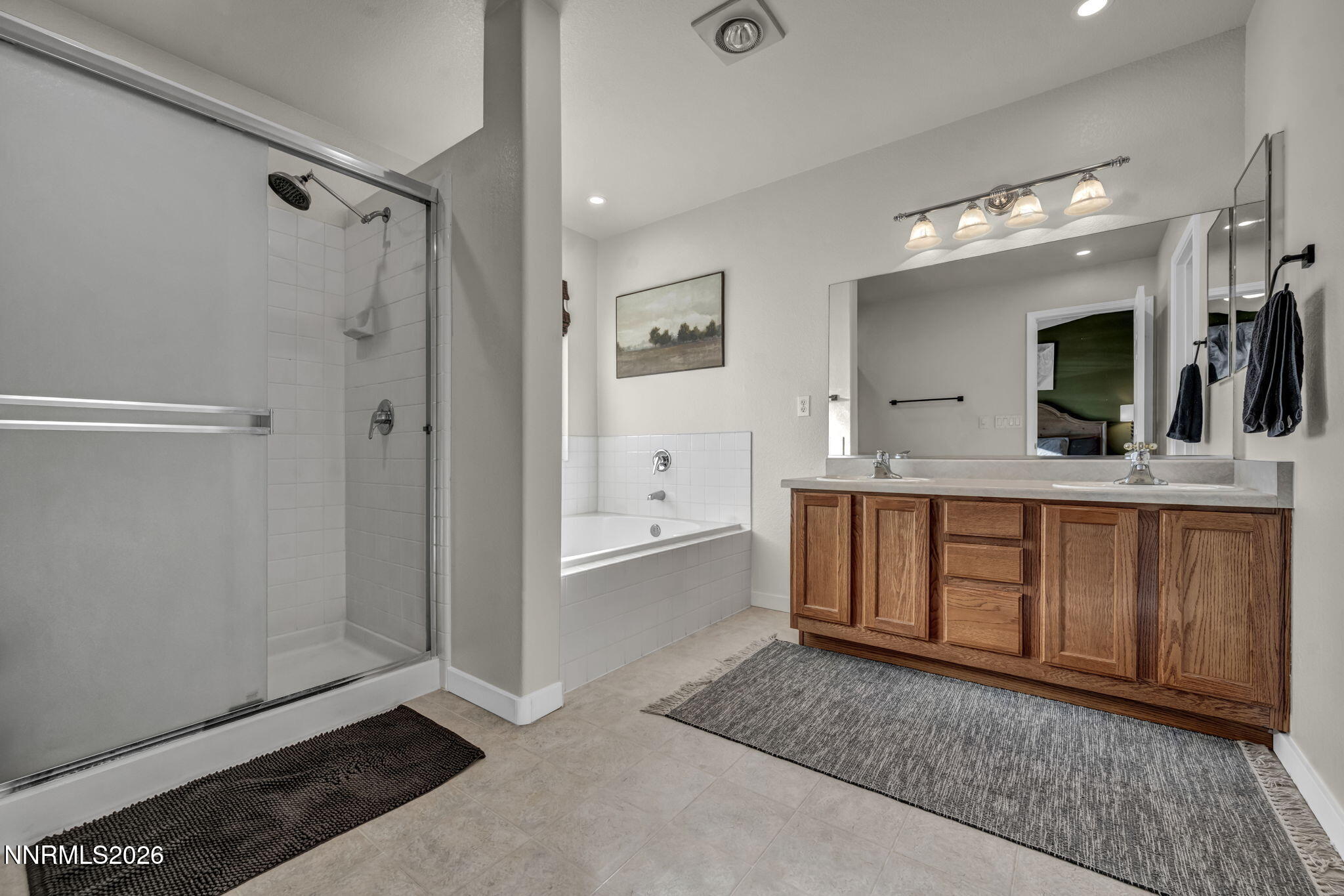952 Red Falcon Way Spanish Springs, NV 89441 - Photo 19 of 46 a bathroom with a double vanity sink a mirror and a bathtub