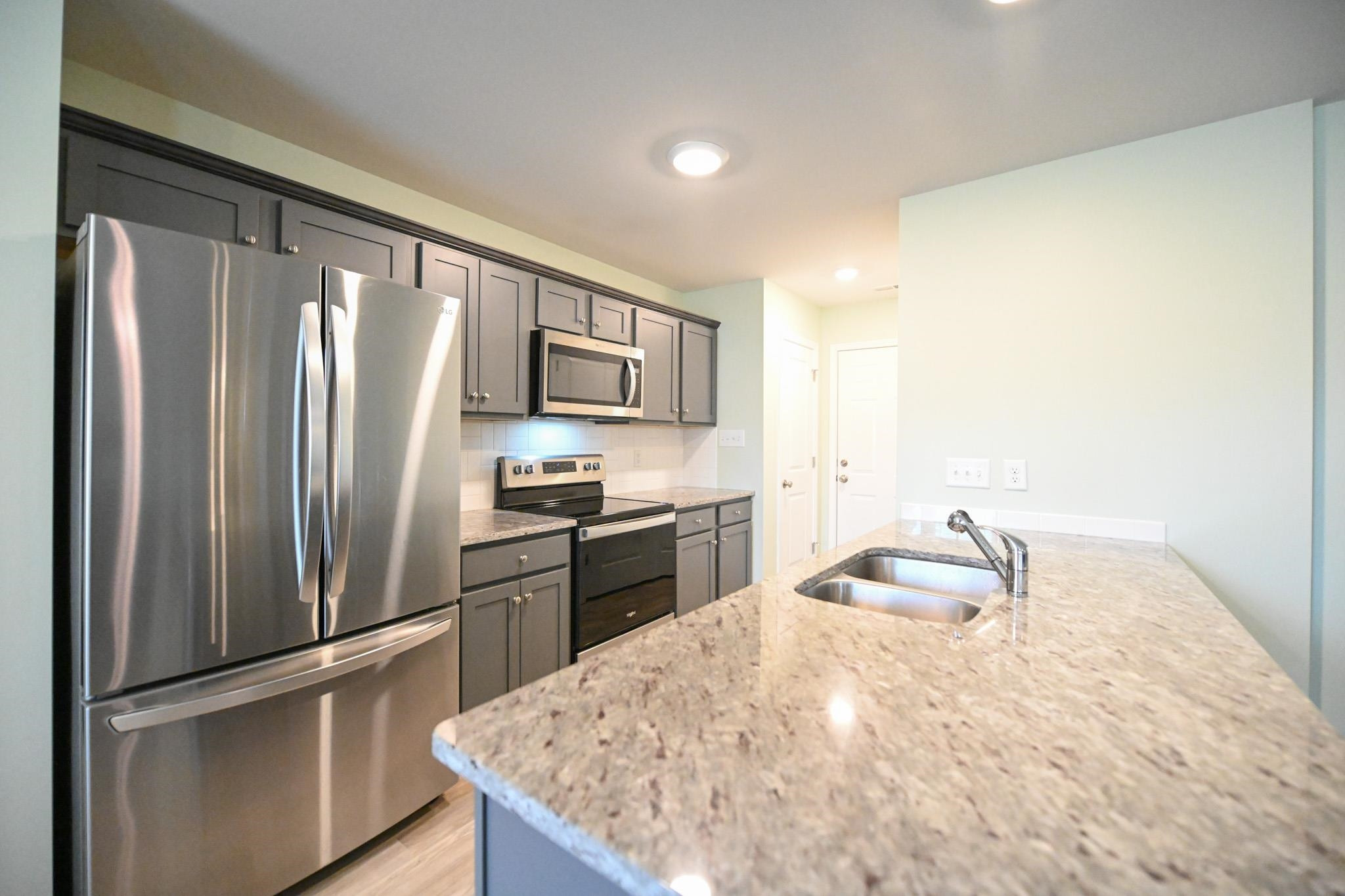 132 Winter Red Way Benson, NC 27504 - Photo 11 of 33 a kitchen with granite countertop a refrigerator stove and sink