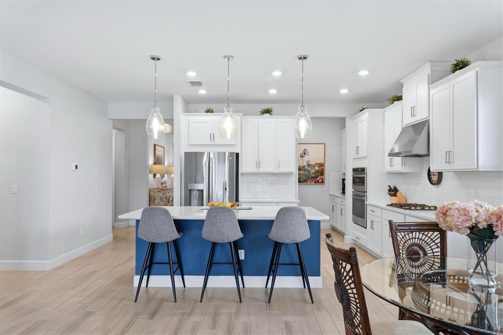 9268 Tequila Sunrise Drive Sarasota, FL 34241 - Photo 13 of 56 a kitchen with stainless steel appliances kitchen island granite countertop a dining table chairs and white cabinets