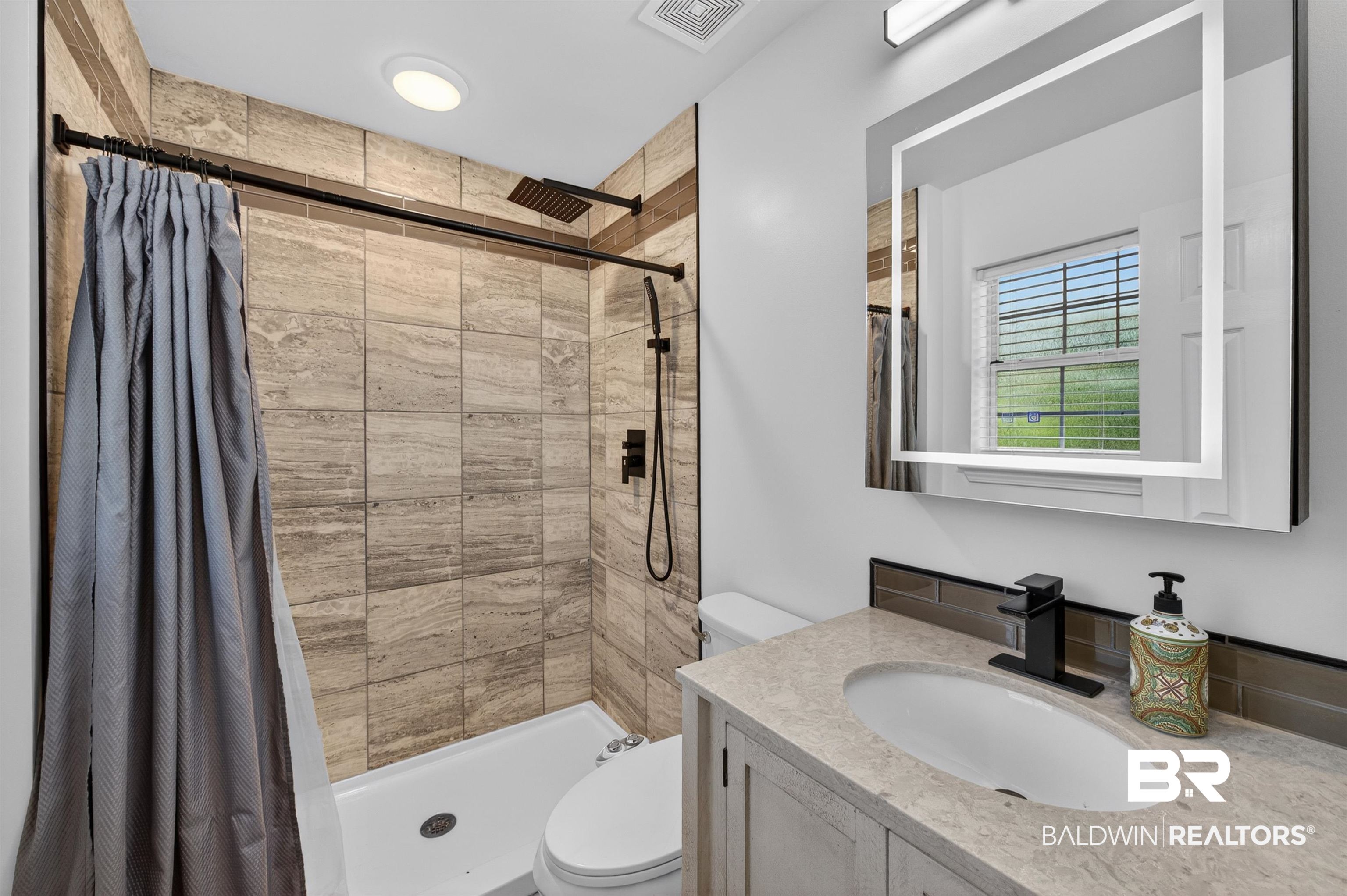 9624 North Bay Street Foley, AL 36535 - Photo 24 of 59 Contemporary bathroom featuring a tiled shower with a rainfall showerhead and a separate handheld sprayer