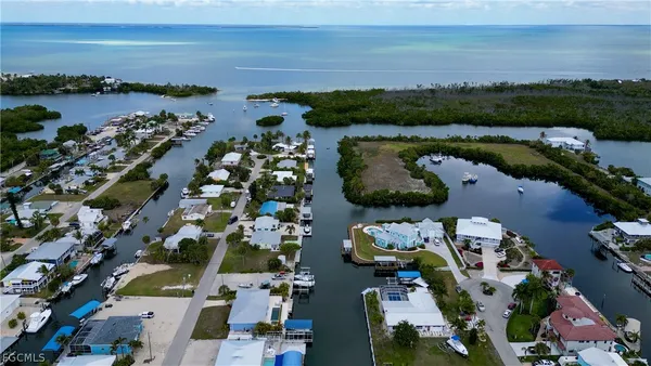 an aerial view of ocean and residential houses with outdoor space