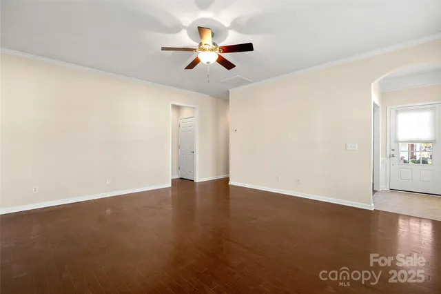 an empty room with wooden floor fan and windows