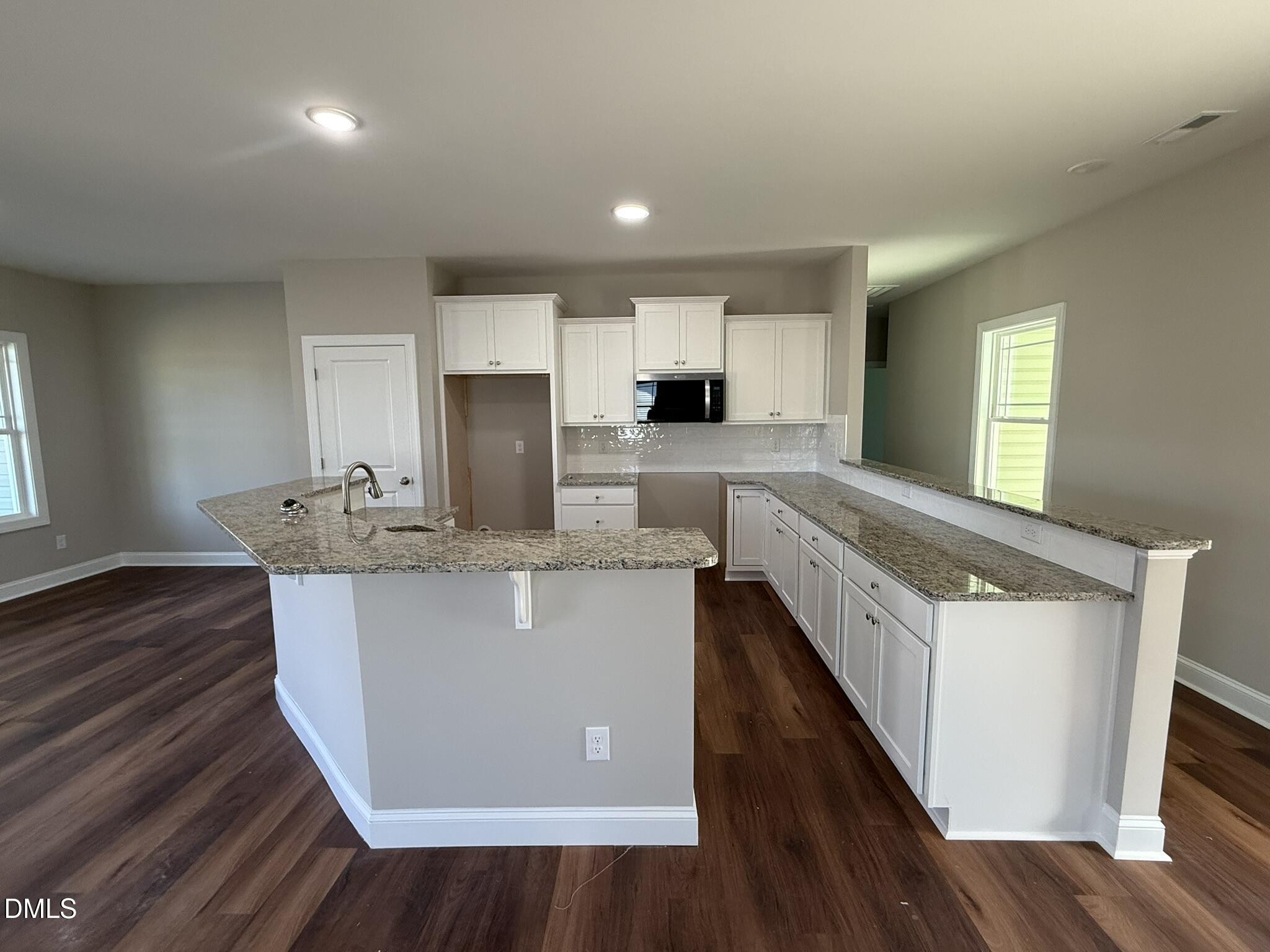70 Hot Spgs Way Benson, NC 27504 - Photo 7 of 29 a kitchen with kitchen island granite countertop a sink a stove a refrigerator cabinets and wooden floor