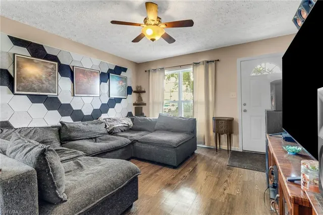 a living room with furniture a ceiling fan and a flat screen tv