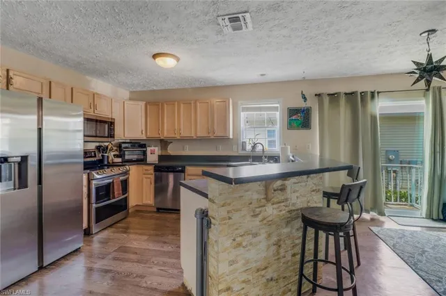 a kitchen with stainless steel appliances granite countertop a stove a sink dishwasher a refrigerator and a microwave