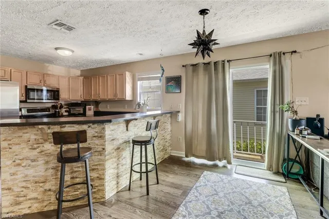 a kitchen with stainless steel appliances granite countertop a stove top oven a sink a dining table and chairs
