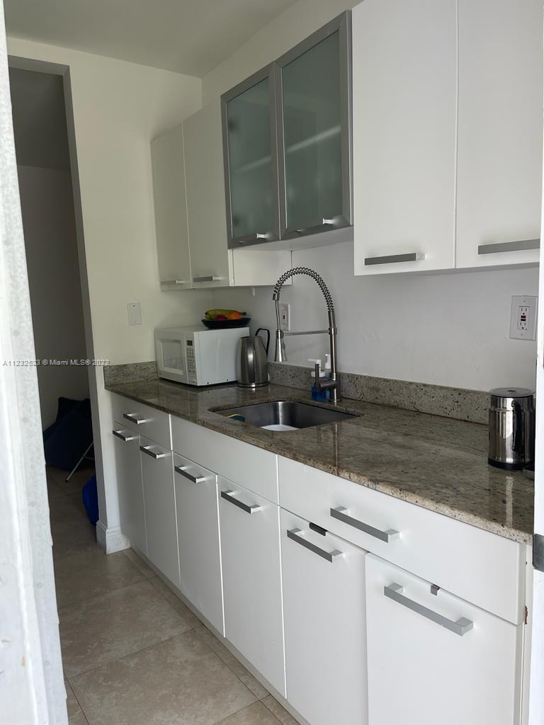 100 Sunrise Drive, Unit 25 Key Biscayne, FL 33149 - Photo 12 of 21 a kitchen with granite countertop white cabinets and sink