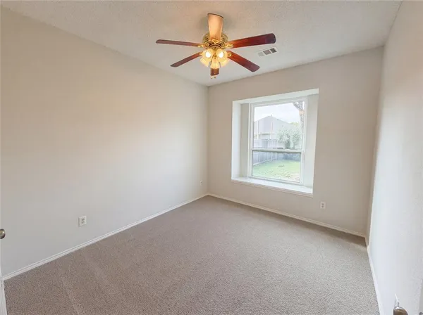an empty room with windows and fan