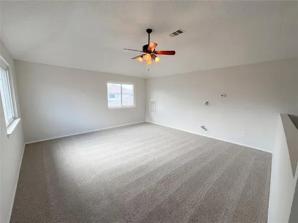 an empty room with windows and fan