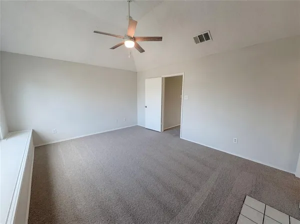 an empty room with a chandelier fan and wooden floor
