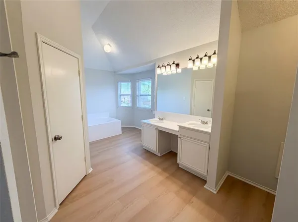 a bathroom with a double vanity sink a mirror and a bathtub