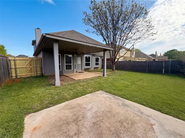 a view of a house with a yard and a large tree