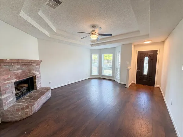 an empty room with wooden floor fireplace and windows