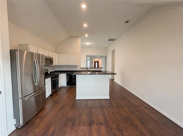a kitchen with stainless steel appliances wooden floor and a refrigerator