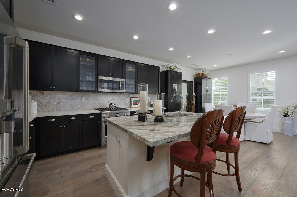 372 Calistoga Road Camarillo, CA 93010 - Photo 9 of 36 a kitchen with stainless steel appliances granite countertop a stove top oven a sink dishwasher a dining table and chairs with wooden floor