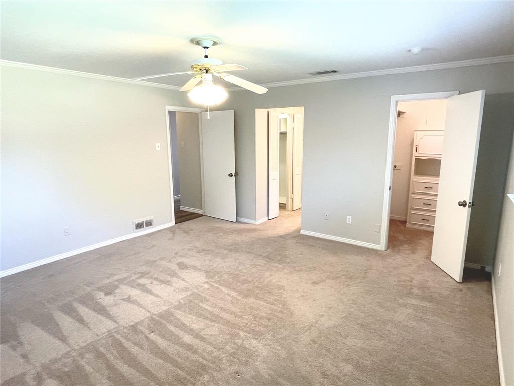 4847 Twin Post Road Dallas, TX 75244 - Photo 13 of 36 Primary bedroom with 2 spacious closets, ceiling fan, light colored carpet, and crown molding
